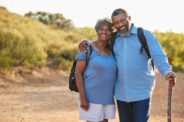 Older couple in blue shirts and smiling during their hike