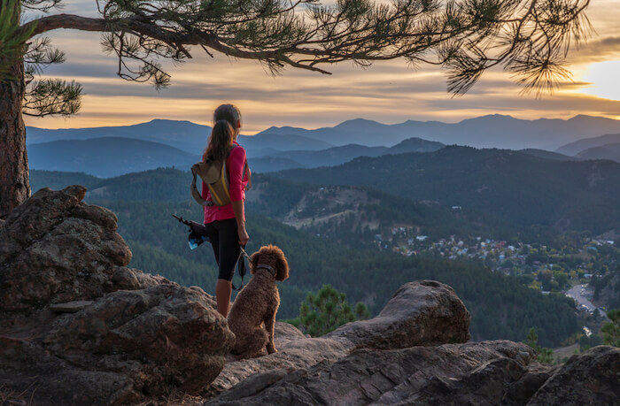 Woman with dog at the top of a mountain after climb