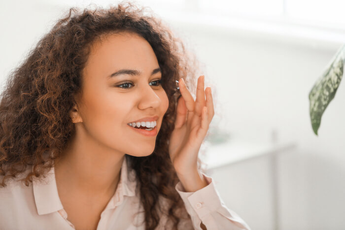 Woman smiling while adding contact lenses to eye