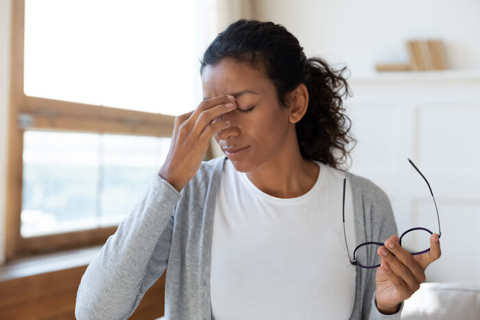 Woman rubbing eyes after removing glasses