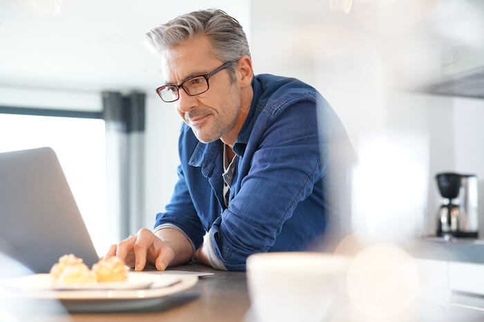 middle-aged man wearing glasses on laptop