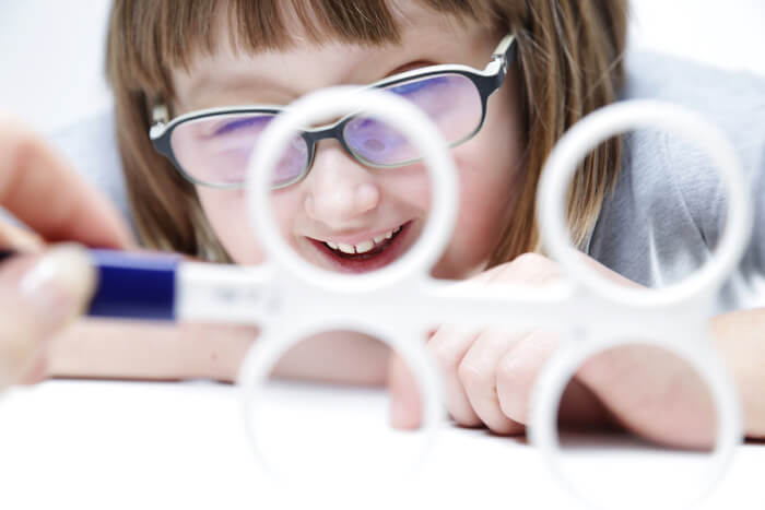 Little girl in glasses looking at vision therapy tool